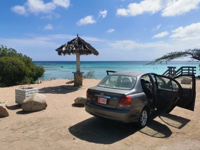 Parked car near Palapa at beach in Aruba