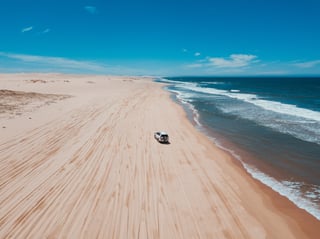 A 4x4 on a beach with waves