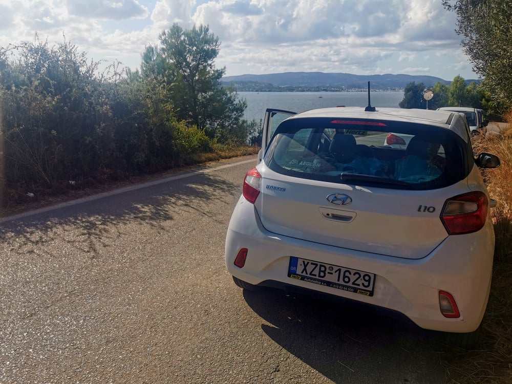 A white car parked by the sea in Greece.