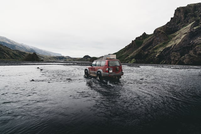 A red Jeep beside the water in Iceland.
