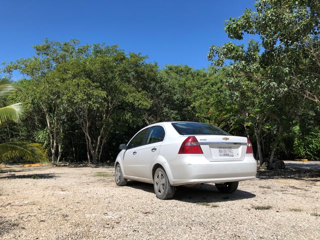 A white rental car seen from behind on a road in Mexico.