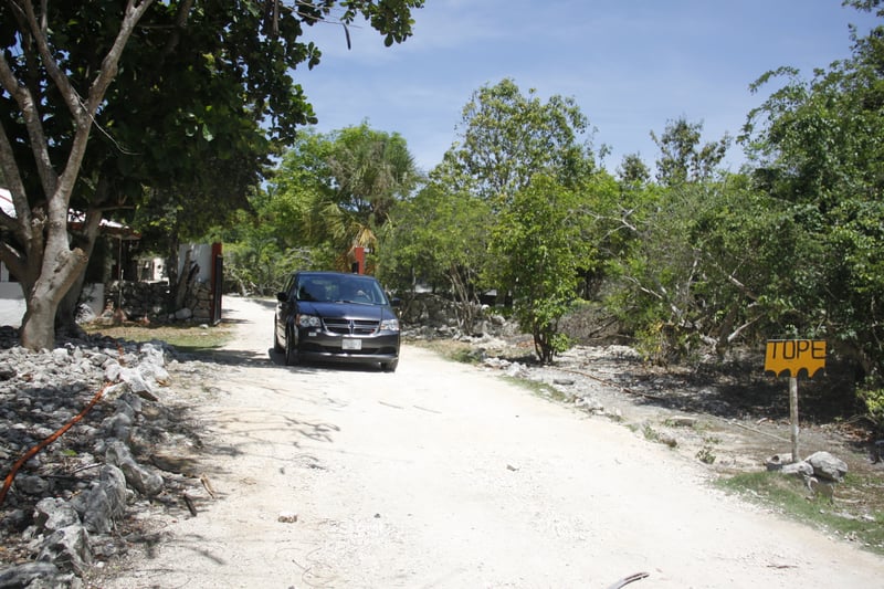 Dark car with Tope sign on unpaved road, Mexico