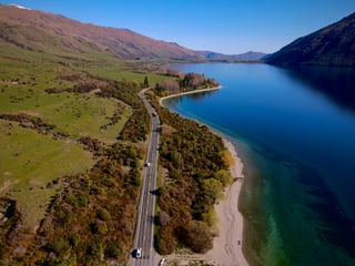 Road along a blue lake and green mountains in New Zealand