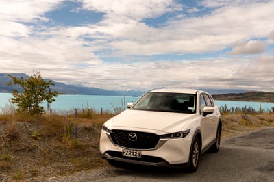 A white rental car in front of Lake Pukaki