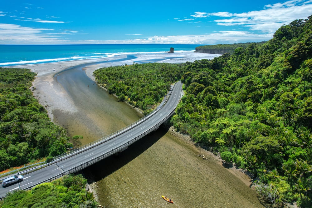 View of Pororari river bridge with the sea and forest