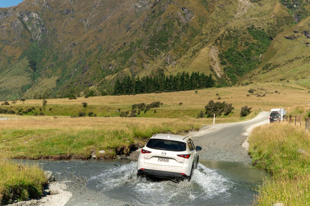 White car crossing a river at Wanaka Mount Iron, New Zealand