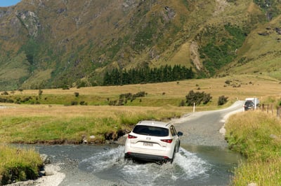 White car crossing a river at Wanaka Mount Iron, New Zealand