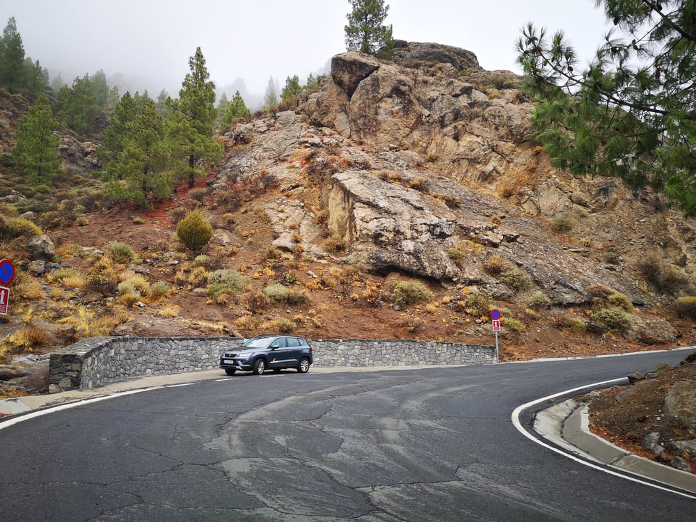 Grey SUV parked on the side of the road near a rocky mountain in Spain