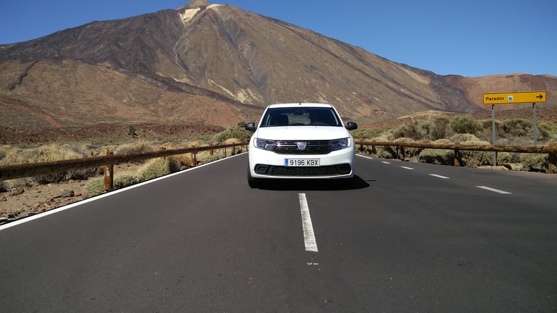 White car on a road and mountains in the back in Spain